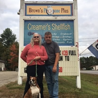 The owners of Brown's Propane with their dog at the Brown's Propane Plus sign